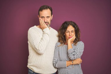 Izole mor arka plan üzerinde kış kazak giyen güzel orta yaş çift yorgun görünümlü ve çapraz kolları ile depresyon sorunları ile sıkılmış düşünme.