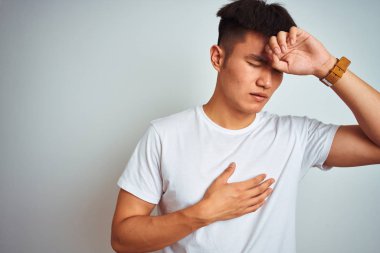 Genç Asyalı Çinli adam izole beyaz arka plan üzerinde ayakta t-shirt giyen hastalık ve ateş, grip ve soğuk algınlığı, virüs hasta için alın dokunmadan