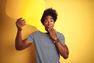 Genç afro-amerikan adam izole sarı arka plan kapağı ağız üzerinde duran konuşma kabarcık tutan el hata için utanç ile şok, korku ifadesi, sessizlik, gizli kavram korkmuş
