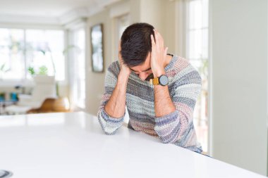 Ev umutsuz ve stresli baş ağrısı muzdarip çünkü, sıradan kazak giyen İspanyol yakışıklı ağrı ve Migren. Ellerini kafasına.