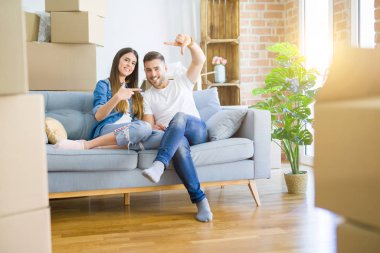 Yeni eve taşındıktan sonra koltukta oturup gülümseyen ve mutlu yüzlü elleri ve parmakları olan genç bir çift. Yaratıcılık ve fotoğrafçılık kavramı.