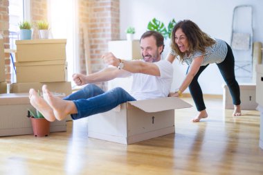 Orta yaş üst düzey romantik çift, eğlenceli karton içinde sürme, heyecanlı ve yeni bir eve taşımak için mutlu gülümseyen