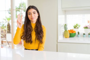 Genç güzel kadın evde gösterilen ve parmakları ile işaret beyaz masada üçüncü ise kendinden emin ve mutlu gülümseyerek.