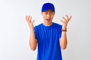 Mavi t-shirt giyen Çinli teslimatçı ve izole beyaz arka plan üzerinde duran şapka kollarını kaldırdı ve kapalı gözleri heyecan çığlık ile başarı için deli ve deli kutluyor. Kazanan kavramı