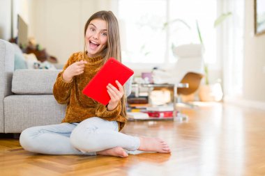 Güzel genç kız çocuk dijital Touchpad tablet kullanarak katta oturan çok mutlu el ve parmak ile işaret