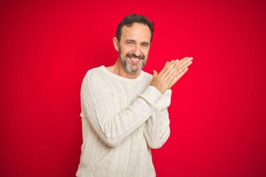 Izole kırmızı arka plan üzerinde gri saçlı yakışıklı orta yaş yaşlı adam alkışlama ve mutlu ve neşeli alkışlayan, birlikte gururlu eller gülümseyen