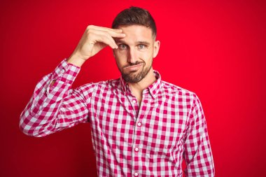 Kırmızı izole arka plan üzerinde Genç yakışıklı adam endişeli ve alnında el ile ilgili bir sorun hakkında vurguladı, sinir ve kriz için endişeli