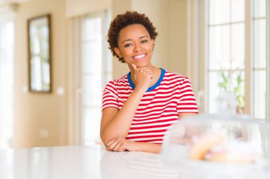 Genç güzel Afrikalı-Amerikalı kadın evde emin çapraz kollar ve çeneme kaldırdı el ile gülümseme ile kameraya bakıyor. Pozitif düşünce.