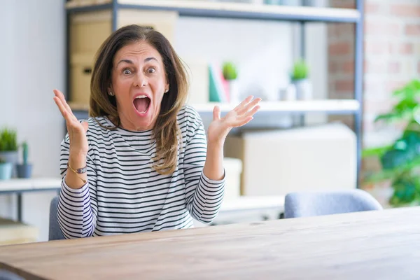 Donna Anziana Mezza Età Seduta Tavola Casa Festeggiare Pazzo Stupito — Foto Stock