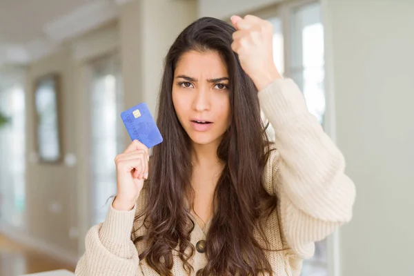 Young woman holding credit card as payment annoyed and frustrated shouting with anger, crazy and yelling with raised hand, anger concept