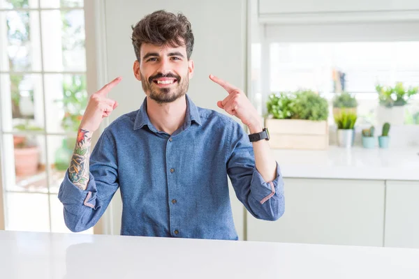 Hombre Joven Con Camisa Casual Sentado Mesa Blanca Sonriendo Señalando — Foto de Stock