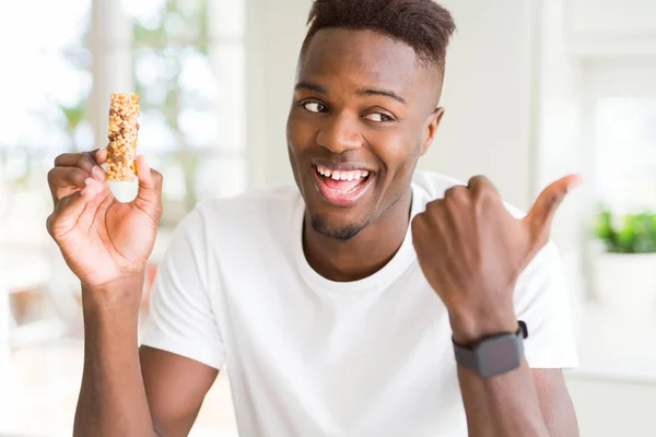 Hombre Afroamericano Comiendo Enérgica Barra Cereales Señalando Mostrando Con Pulgar — Foto de Stock