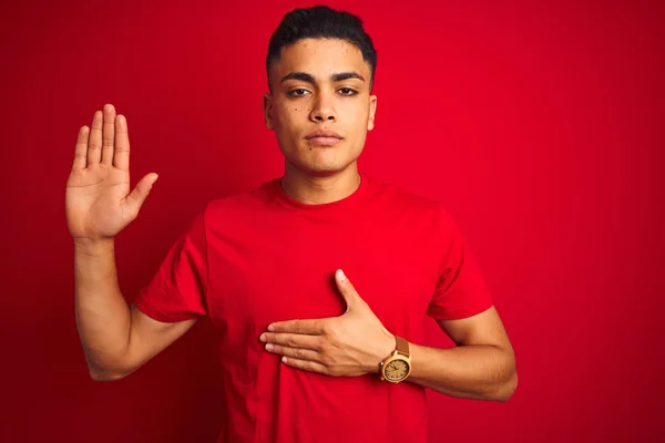 Jovem Brasileiro Vestindo Camiseta Sobre Fundo Vermelho Isolado Jurando Com — Fotografia de Stock