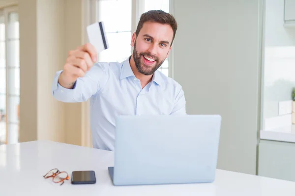 Hombre de negocios guapo compras en línea utilizando ordenador portátil y —  Fotos de Stock