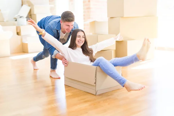 美丽的年轻夫妇微笑在爱有乐趣骑在纸板箱内 庆祝搬到一个新的家 — 图库照片