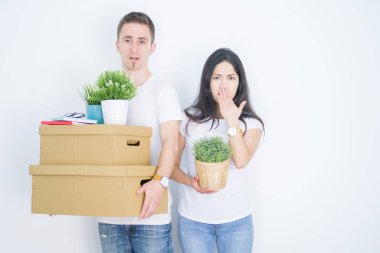 Genç ve güzel bir çift, izole edilmiş beyaz arka plan üzerinde duran karton kutular tutuyorlar. Ağızları kapatıyorlar. Yanlışlık yüzünden utançla sarsılıyorlar, korku ifadesi, sessizlik içinde korkmak, gizli konsept.