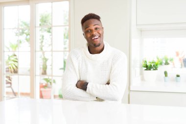 Afro-Amerikan yakışıklı beyaz masa mutlu yüz çapraz silah kameraya bakarak ile gülümseyen. Olumlu bir kişi.