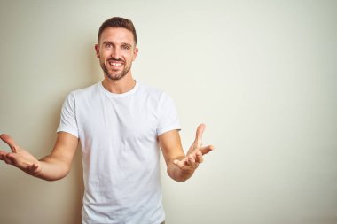 İzole edilmiş arka planda günlük beyaz tişört giyen genç yakışıklı adam gülümseyerek yardım eli uzatıyor ve kabul ediyor..