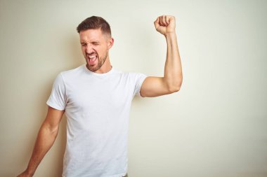 Hareketli rahat ve kendinden emin müzik gülümseyen izole arka plan üzerinde dans mutlu ve neşeli, casual beyaz t-shirt giyen genç yakışıklı adam