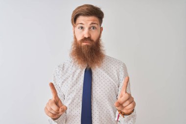 Genç kızıl saçlı İrlandalı işadamı izole beyaz arka plan üzerinde duran üzgün ve üzgün görünümlü kadar işaret, parmakları ile yön gösteren, mutsuz ve depresif.