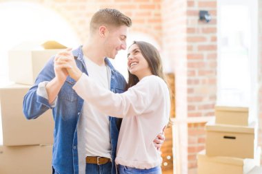 Yeni bir evde eğlenceli dans sahip güzel genç çift, yeni bir eve hareket kutluyor