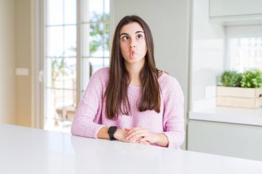 Pembe kazak giyen güzel genç kadın dudakları ile balık yüz yapma, deli ve komik jest. Komik ifade.