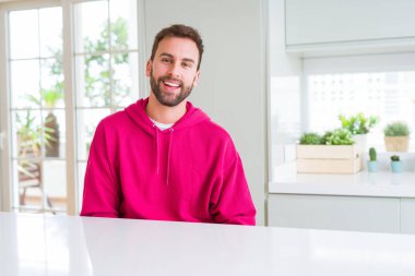 Yakışıklı adam giyen sıradan kazak evde ve gülümseyen varsaymak