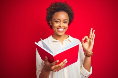 Kırmızı izole arka plan üzerinde bir kitap okuyan Afro-Amerikan kadın parmakları ile ok işareti yapıyor, mükemmel bir sembol