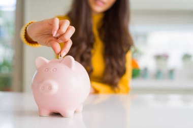 Yatırım olarak Piggy banka içinde bir sikke koyarak gülümseyen kadın yakın