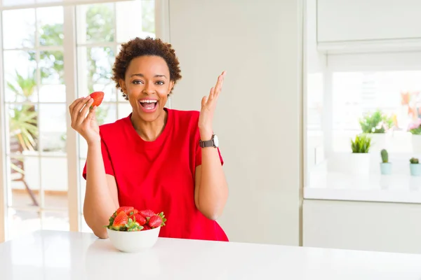 年轻的非洲裔美国妇女吃新鲜的草莓早餐很高兴和兴奋 胜利者的表情庆祝胜利尖叫与大微笑和举手 — 图库照片