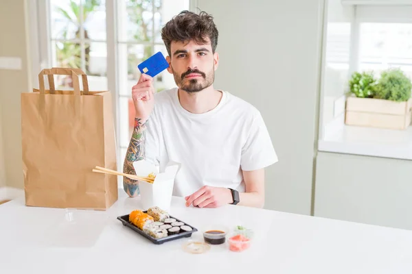 Joven Comiendo Sushi Asiático Entrega Domicilio Usando Tarjeta Crédito Como — Foto de Stock