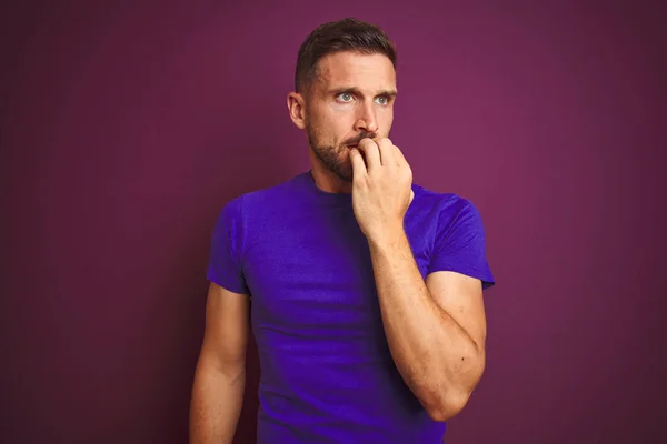 年轻男子穿着宽松的紫色T恤 披着淡紫色的背景 看上去很紧张 双手放在咬指甲的嘴上 焦虑问题 — 图库照片