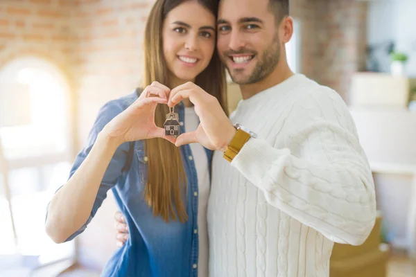 Junges Paar zieht in ein neues Zuhause, umarmt sich verliebt und zeigt Schlüssel — Stockfoto