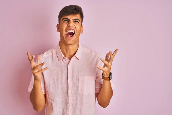 孤立したピンクの背景の上に立っているカジュアルなシャツを着ている若いインド人男性は 狂気と怒りの叫びと積極的な表現と腕を上げて叫びました 欲求不満の概念 — ストック写真