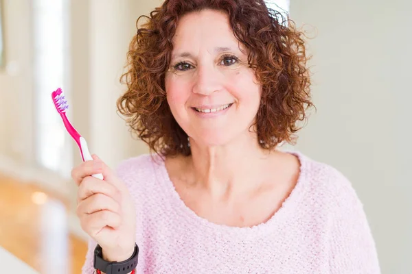 在牙科诊所拿着粉红牙刷的老年妇女 满脸喜笑 脸上露出自信的笑容 露出牙齿 — 图库照片