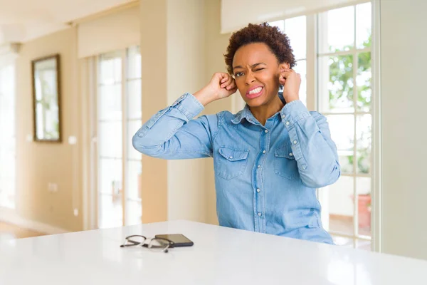 Young beautiful african american woman covering ears with fingers with annoyed expression for the noise of loud music. Deaf concept.