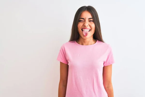 年轻美丽的女人穿着粉色休闲装站在孤立的白色背景上 带着滑稽的表情伸出舌头 情感概念 — 图库照片