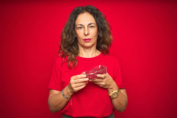 Mujer Mayor Mediana Edad Comiendo Frambuesas Sobre Fondo Rojo Aislado — Foto de Stock