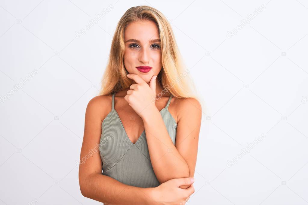 Young beautiful woman wearing casual green t-shirt standing over isolated white background looking confident at the camera with smile with crossed arms and hand raised on chin. Thinking positive.