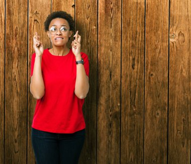 Umut ve gözleri kapalı geçiş parmaklarıyla gülümseyen izole arka plan üzerinde gözlük güzel genç Afro-Amerikan kadın. Şans ve batıl kavramı.