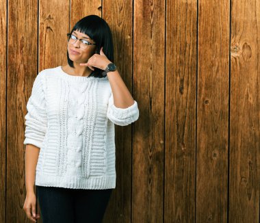 Güzel genç Afro-Amerikan kadın yapıyor gülümseyen izole arka plan üzerinde gözlük telefon hareketi ile el ve parmak telefonda konuşuyor gibi. Kavramları iletişim.