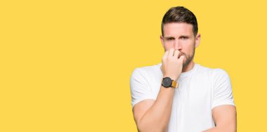 Yakışıklı adam stresli ve gergin ile seyir casual beyaz t-shirt giyen tırnak ısırma dudaklarından eller. Anksiyete sorunu.