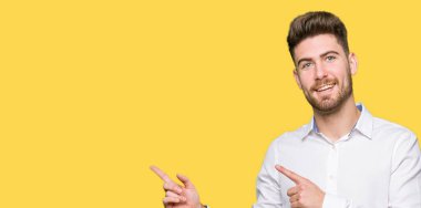 Gülümseyen ve iki elleri ve parmakları ile tarafına işaret kamera bakarak genç yakışıklı iş adamı.