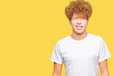 Seksi ifade, neşeli ve mutlu yüz ile kameraya bakarak rahat beyaz t-shirt göz kırparak giyen afro saçlı genç yakışıklı adam.