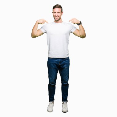 Yakışıklı adam yüzünde gülümseme ile kendinden emin görünüyorsun, kendini gururlu ve mutlu parmakları ile işaret casual beyaz t-shirt giyen.
