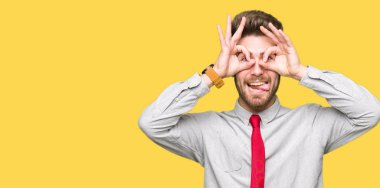 Genç yakışıklı iş adamı, dilini parmaklarının arasından baktığını yapışmasını dürbün gibi ok jest yapıyor. Deli ifade.