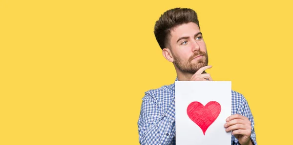 Young Handsome Man Holding Paper Red Heart Serious Face Thinking — Stock Photo, Image