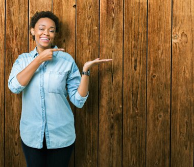 Genç güzel Afrikalı-Amerikalı kadın üzerinden hayran ve el ile sunulması ve parmak ile işaret ederken kameraya gülümseyen izole arka plan.