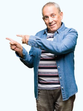 Gülen ve iki el ve parmak tarafına işaret kamera bakarak kot ceket giyen yakışıklı kıdemli adam.