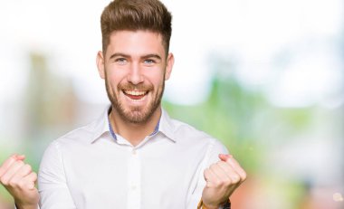 Genç yakışıklı iş adamı kutluyor şaşırttı ve başarı için kaldırdı kollarını açarak hayret ve gözleri açık. Kazanan kavramı.